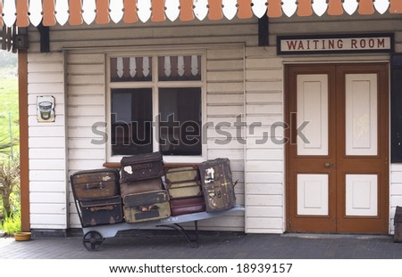 vintage suitcases and old wooden trolley outside a vintage station waiting room