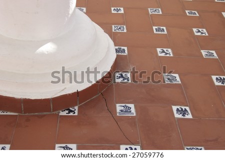 floor tiles which are cracked at the bottom of a supporting column