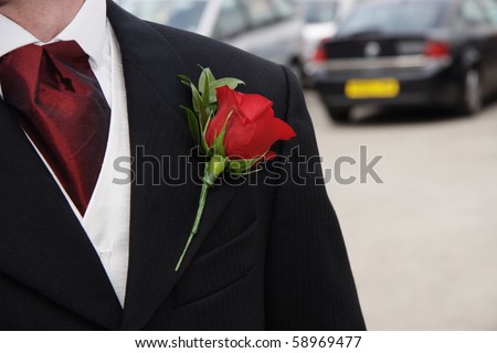 red rose pinned as a button hole on the lapel of a grooms Jacket