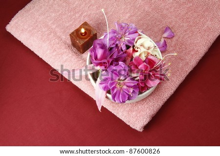 flowers in a bowl with  scented candle and pink towel