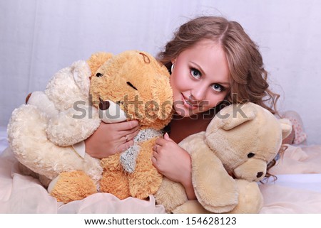 Pretty girl with three teddy bears on the bed