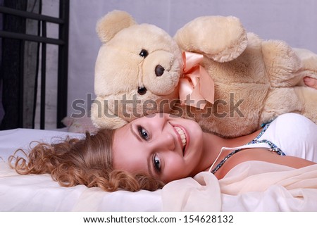 Pretty girl with a teddy bear on the bed
