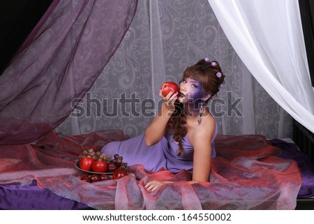 portrait of a girl in a purple dress in the bedroom with grapes