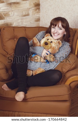 portrait of a beautiful tender girl sitting in the chair with teddy bear