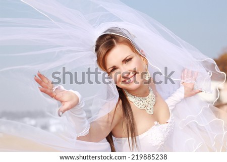 the bride with a veil on the beach in the sky and blue sea