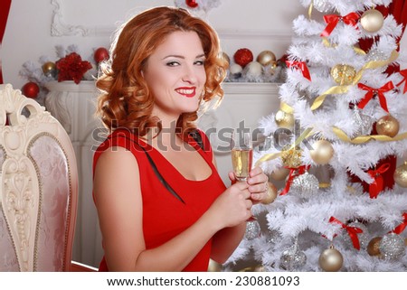 Christmas and New Year. Woman in the beautiful interior with a Xmas tree. glass of champagne