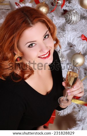 Christmas and New Year. Woman in the beautiful interior with a Xmas tree. glass of champagne