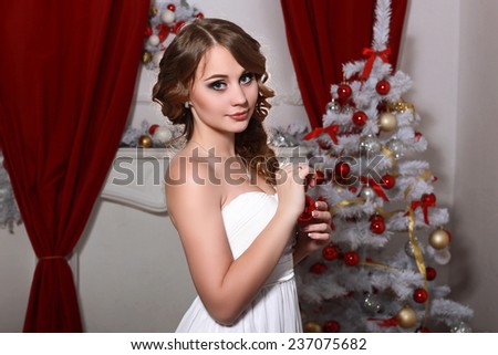 Christmas and New Year. Woman in the long white dress in the luxury interior with a Xmas tree