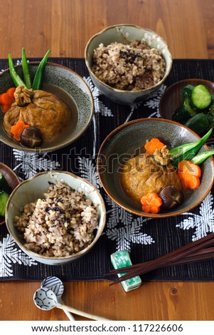 A japanese lunch for two: mixed grain rice, lightly pickled cucumber and shirataki and mochi kinchaku, a Japanese stuffed fried tofu beggar's purse garnished with carrot, shiitake mushroom and okra