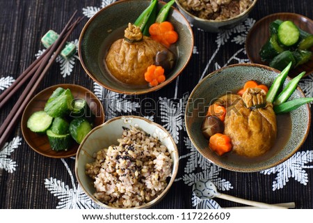 A japanese lunch for two: mixed grain rice, lightly pickled cucumber and shirataki and mochi kinchaku, a Japanese stuffed fried tofu beggar\'s purse garnished with carrot, shiitake mushroom and okra