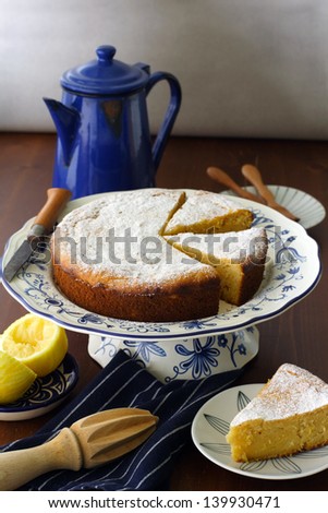 lemon ricotta cake, made with olive oil, ground almond and honey, served on a pattern cake platter, on a rustic wood surface