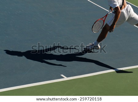 VANCOUVER, CANADA - AUGUST 7, 2014: An athlete casts a shadow during tennis match in Stanley Park in Vancouver, Canada, on August 7, 2014.