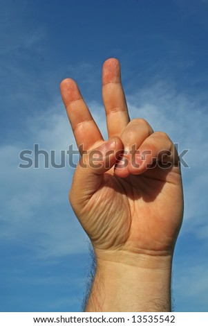 Victory or peace hand gesture against blue sky