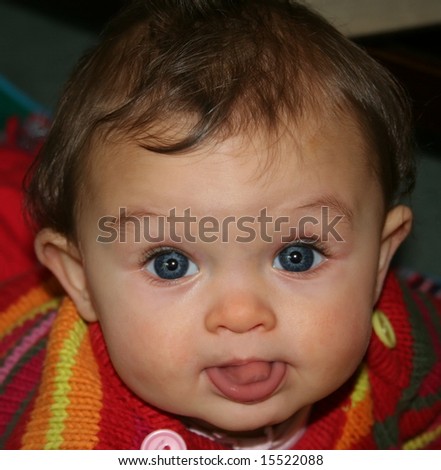 Inquisitive six month old baby with big blue eyes looking at camera