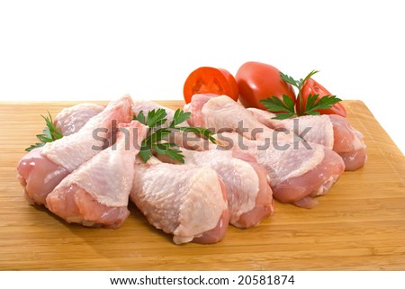 Fresh raw chicken wings on chopping board with roma tomatoes