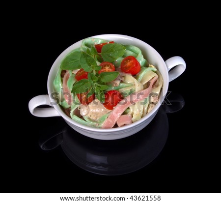 Tri-Color Fettuccine in white bowl on black background with reflection of bowl in surface.