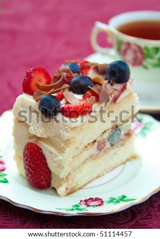 Delicious slice of berry sponge cake with strawberries, blueberries and milk chocolate shavings with selective focus on the cake.