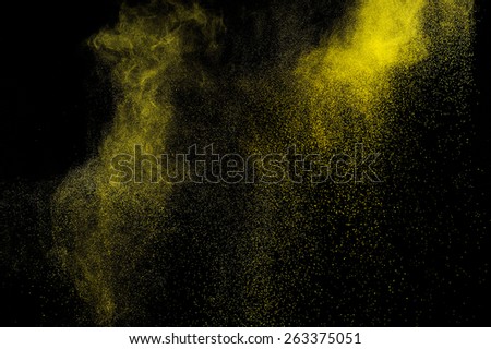 Abstract yellow and gold  paint Holi. Abstract yellow and gold powder explosion on black background.