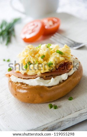 Toasted bagel with ham, cream cheese, chives and scrambled egg topping