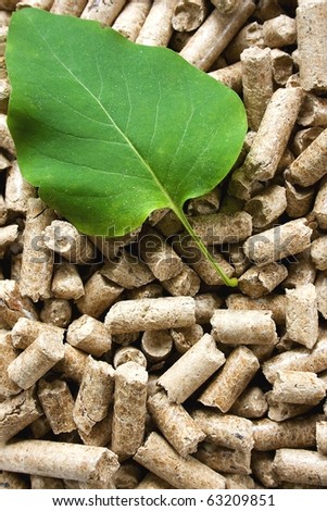 A pile of wood pellets with a green leaf