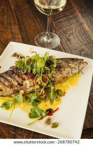 wood-fired, oven-roasted whole fish with a glass of chardonnay wine