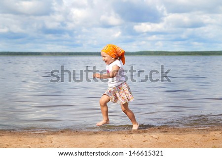 child runs along the bank of the river and laughs