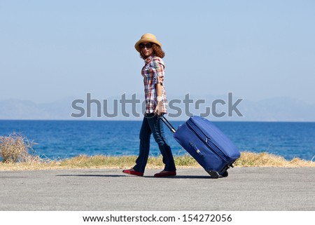 Attractive woman with suitcase on the beach