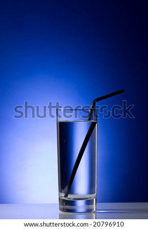 Glass with pure water with a black straw on a blue background