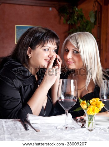 two young women listen to a conversation on the phone