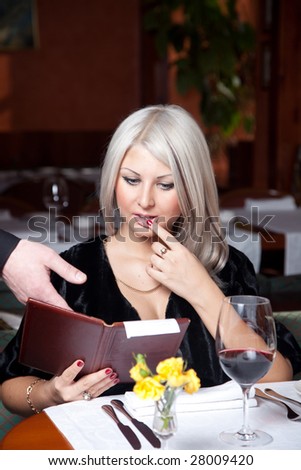 Blond girl in a restaurant show a huge bill for food