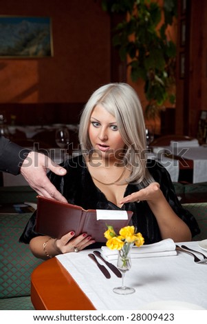 Blond girl in a restaurant show a huge bill for food