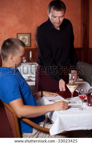 The waiter brings bill at restaurant. Focus on the waiter