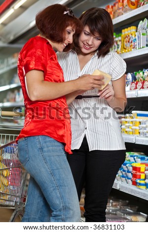 Two customers in supermarket. Focus on the girl in the white.