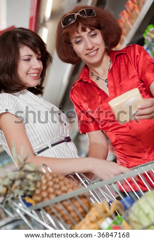 Two customers in supermarket. Cheese choice