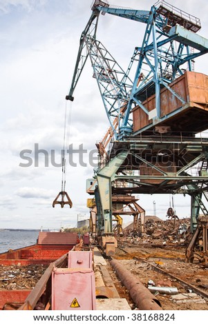 Industrial grabber the crane loads the barge scrap metal