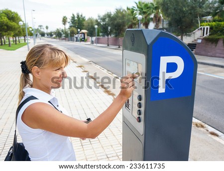 young woman paying for parking at pay station