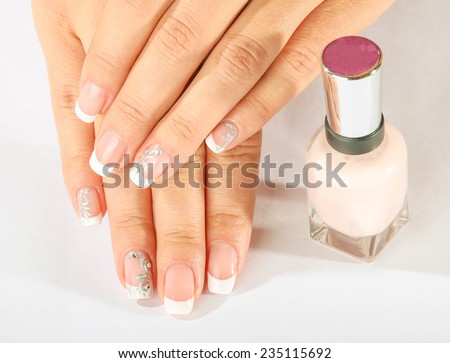 beautiful female hands with French manicure with varnish bottle