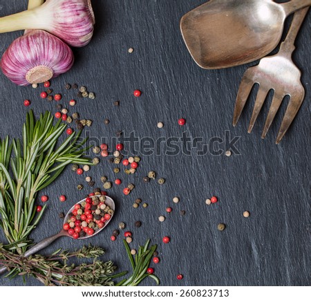 spoons with spices and herbs on textured black
