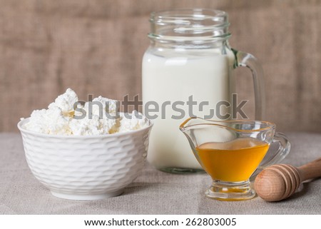 Cottage cheese with milk and honey on burlap background