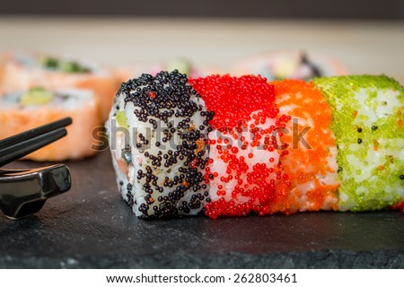 sushi with colorful flying fish eggs close up on black