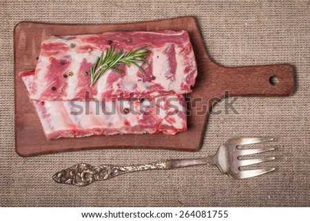 Fresh pork ribs, meat marinated and prepared for roast with garlic allspice on wooden background top view