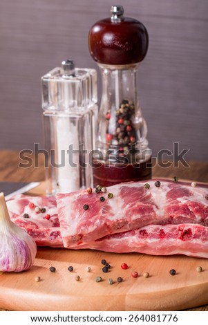 Fresh pork ribs, meat marinated and prepared for roast with garlic allspice on wooden background