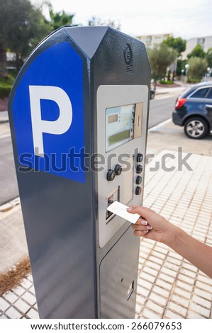 Woman hand is slipping curd into parking meter - close up