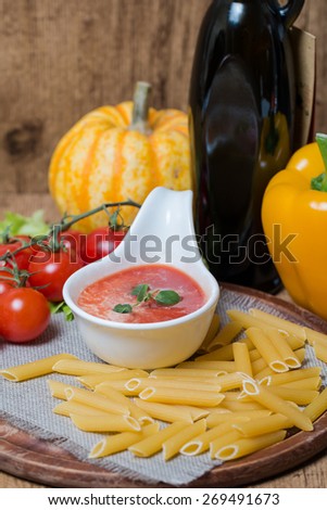 Tomato sauce in a white sauce boat with fresh ingredients and pasta