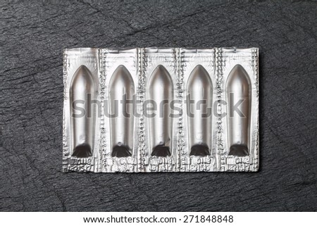 Silver package of suppository on black background