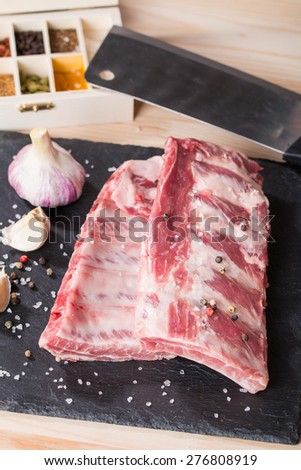Fresh pork ribs, meat marinated and prepared for roast with garlic allspice on wooden background