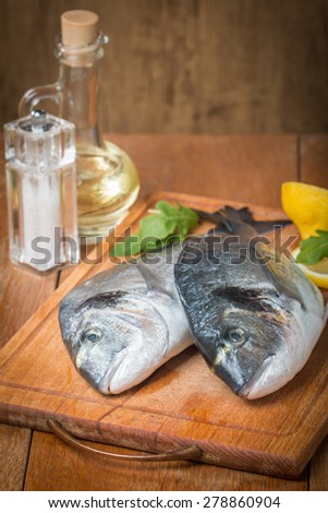 Fresh dorado fish cooking with spices and condiments on wooden table