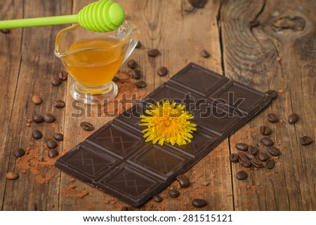 Milk chocolate with honey and coffee beans on wooden background