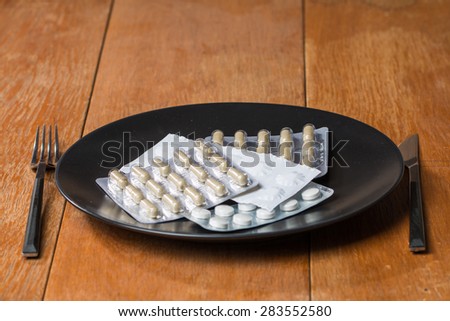 Variety of  pills on plate with fork and knife on wooden background