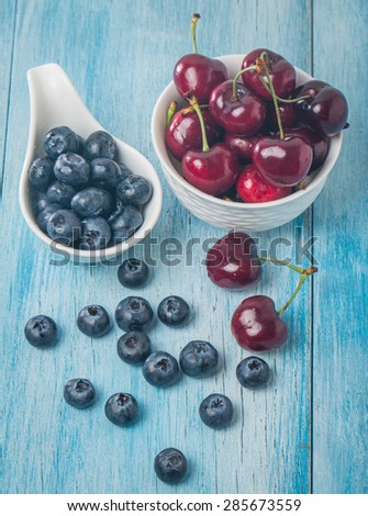 Berries mix in bowl on blue wooden background